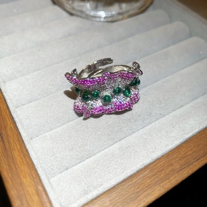 Gros plan détaillé d'une bague ondulée avec zircons roses et verts sur monture argent