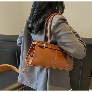 Brown faux leather shoulder bag with buckle detail worn by model in grey blazer