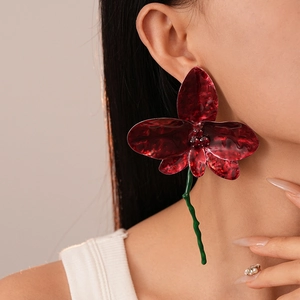 Elegant vintage red flower petal earrings with metallic luster and green stems on model
