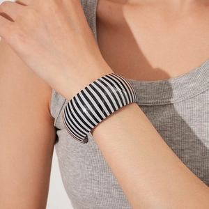Close-up of a wide striped resin bangle on a wrist showing the polished black and white pattern