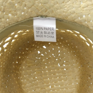 Detailed macro view of 100% paper straw hat interior with wash label and woven texture