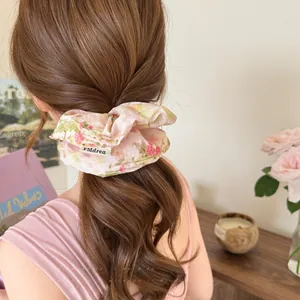 Grote scrunchie met bloemenprint en kant gedragen op een lage paardenstaart kapsel