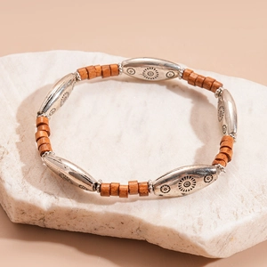 Detail of silver sun-engraved metal beads and vintage brown wood cylinders on a bracelet