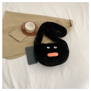 Close-up of black plush monster bag with large eyes and pink lips on a white sheet