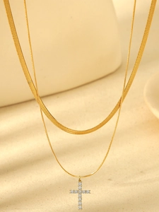 Close-up of gold double layer necklace with snake chain and zircon cross pendant