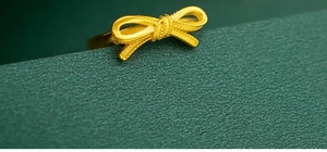 Macro detail of a 18K gold-plated bow ring showing beaded edges and matte metal texture