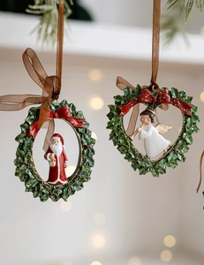 Close-up of resin Christmas wreath ornaments with Santa and angel figurines in warm light