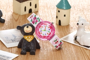 Close-up of pink kids quartz watch with floral strap and colorful numbers dial
