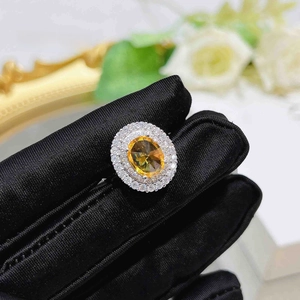 Close-up of oval yellow gemstone ring with double-row zircon pavé on black glove
