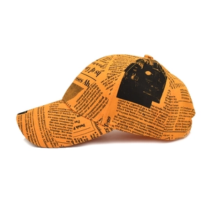 Side view of orange baseball cap with vintage newspaper print and curved brim design