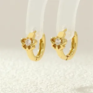 Detail of gold flower hoop earrings with zircon center on a display stand