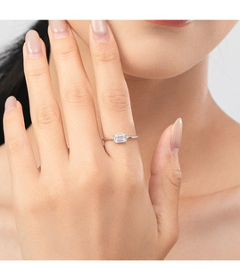 Close-up of emerald-cut white zircon ring on finger featuring a minimalist silver band