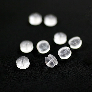 Transparent silicone earring backs in round saucer shape on black fabric background