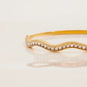 Dettaglio del bracciale in acciaio inossidabile dorato 18K con onde e cristalli bianchi