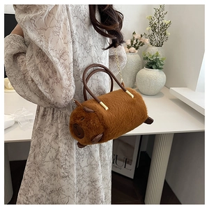 Borsa a cilindro in peluche marrone capibara con tracolla a catena dorata in mano