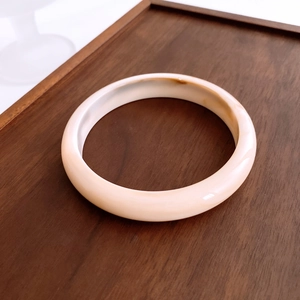 Close-up of minimalist tortoiseshell acrylic bangle with ivory and brown marble texture