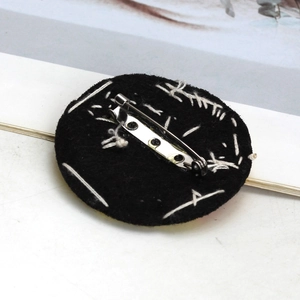 Detail view of the black round felt backing with a secure metal safety pin attachment