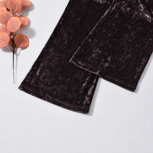 Close-up of dark coffee embossed velvet trousers cuff featuring floral props