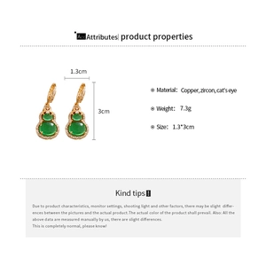 Macro shot of gold-plated gourd earrings with cat-eye stone and zircon detailing