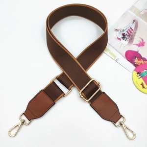 Detail of adjustable brown fabric and leather bag strap with polished gold hardware