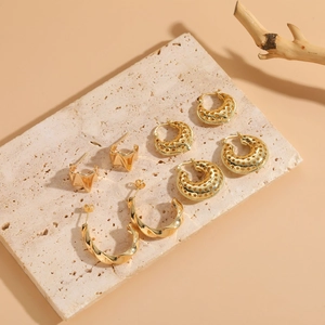 Detailed close-up of 14K gold plated geometric earrings on natural stone background