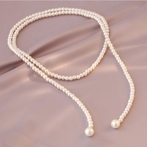 Detail of elegant white pearl necklace draped over soft luxurious silk fabric background