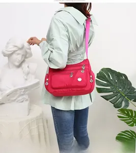 Dettaglio della borsa in nylon impermeabile rosso rosa con tasche con zip e tracolla