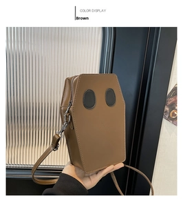 Detail view of brown coffin-shaped PU leather crossbody bag with ghost eye design