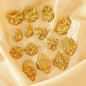 Detailed close-up of textured gold square and irregular geometric earrings on silk