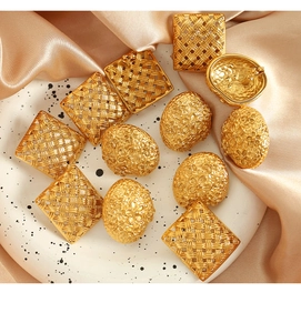 Macro shot of 18k gold plated square woven earrings and embossed floral oval jewelry