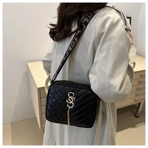 Detail of black quilted crossbody bag with golden tassel and metal hardware decoration