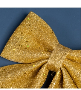 Macro shot of large Christmas bow with golden glitter and laser sequins on dark blue background
