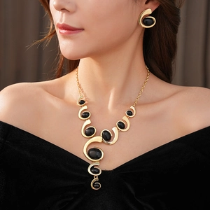Close-up of gold geometric necklace and earrings set with elegant black stones