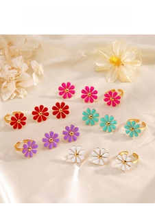 Detail of colorful enamel daisy ring and earring set displayed on golden silk fabric