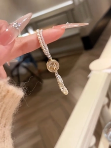 Detail of double-layer bracelet with pearls, crystal chain and gold star pendant