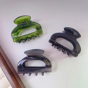 Three acetate hair claws in green, black, and grey with gold handmade text engraving