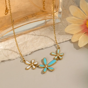 Detailed close-up of 18K gold plated flower necklace with turquoise and white enamel petals