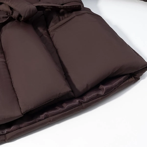 Detailed close-up of dark brown quilted puffer jacket hem with smooth lining texture
