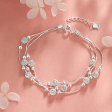 Detail of silver layered beaded bracelet with textured spheres and heart charm