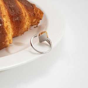Bague ajustable bicolore or et argent style croissant sur une assiette en porcelaine