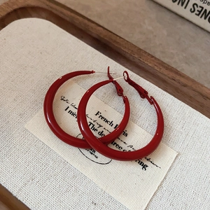 Close-up of red enamel hoop earrings on a vintage card inside a wooden tray