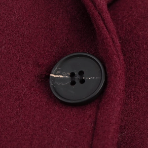 Close-up of wine red wool fabric texture with a classic black round button detail