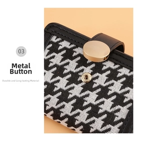 Macro shot of gold metal snap button and black leather trim on houndstooth wallet