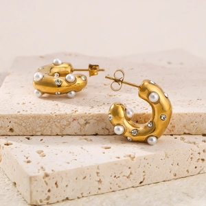 Pair of wide C-shape 18K gold plated earrings with pearls and crystals on beige stone