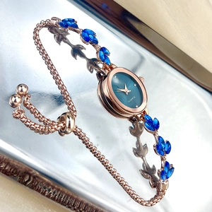 Detail of rose gold leaf strap with blue gemstones and green quartz watch dial