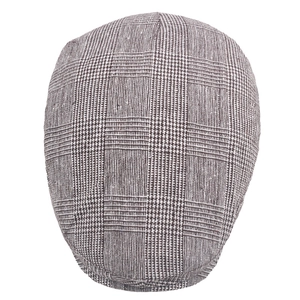 Macro detail of brown and white plaid newsboy cap showing tweed fabric texture