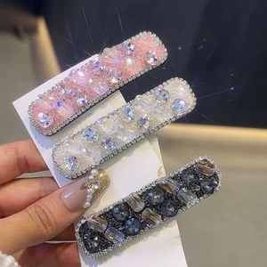 Close-up of sparkling rhinestone hair clips in pink, clear, and grey on display card
