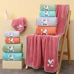 Close-up of thick coral fleece towels with letter embroidery and contrast piping