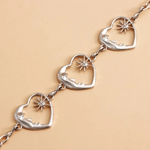 Macro shot of silver metal multilayer chain featuring hollow heart and sun charms for style