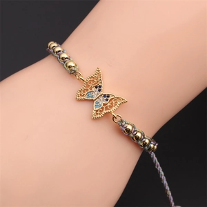 Macro shot of gold-plated butterfly bracelet with blue cubic zirconia on woven cord